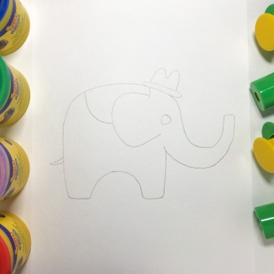 Quatro potes de plasticina coloridos, desenho a lápis de elefante num papel e três carimbos verdes com alças amarelas