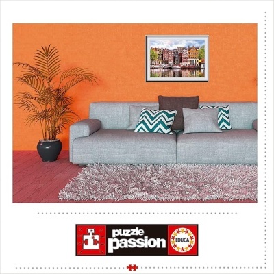 Sala com sofá cinza, almofadas, planta, parede laranja e quadro de casas coloridas