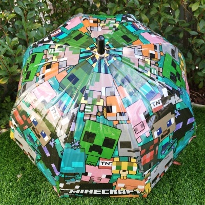 Guarda-chuva infantil com padrão Minecraft colorido e transparente sobre relva sintética