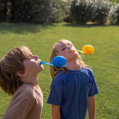 Crianças a equilibrar ovos em colheres ao ar livre