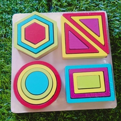 Jogo de encaixe de formas geométricas coloridas em madeira sobre base branca e relva verde