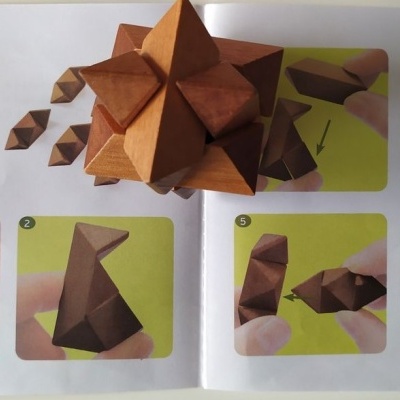 Livro aberto com instruções para montagem de puzzle 3D de madeira castanha.