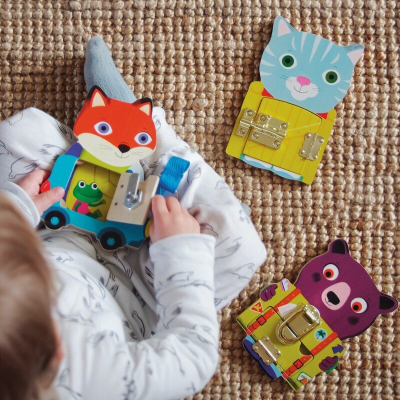 Brinquedos de madeira coloridos com animais e fechos metálicos sobre tapete de juta, criança a brincar