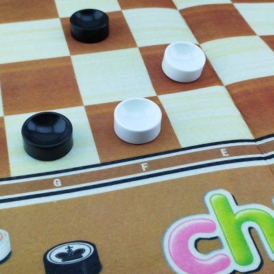 Tabuleiro de jogo quadriculado castanho e bege com peças brancas e pretas e palavra 'chess' colorida