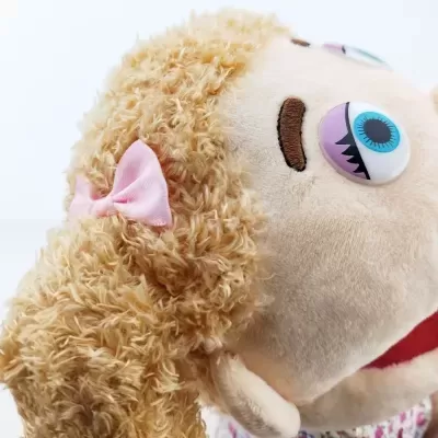Boneca de pelúcia com cabelo encaracolado castanho claro e laço rosa