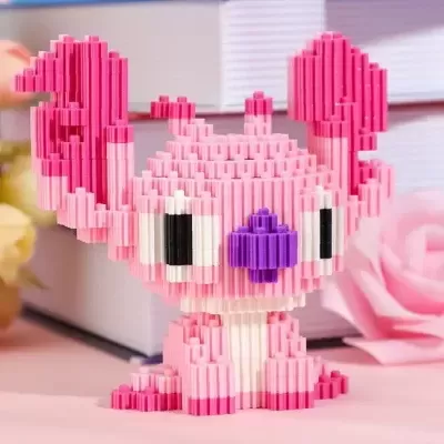 Figura decorativa rosa feita de blocos plásticos com orelhas grandes e nariz roxo, numa mesa com flores e livros.