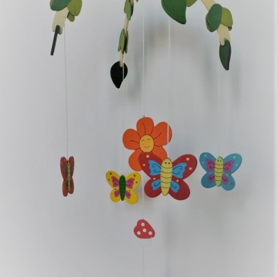 Móbile infantil de madeira com folhas verdes, borboletas coloridas, flor sorridente e cogumelo vermelho