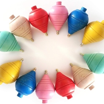 Doze piões coloridos de madeira dispostos em círculo sobre fundo branco.