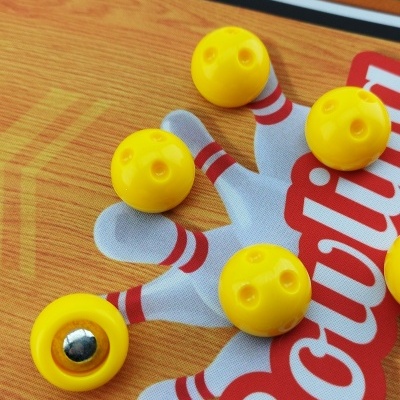 Peças amarelas de jogo sobre tabuleiro com texto Bowling em vermelho