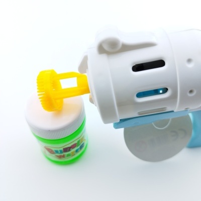 Pistola branca e azul com bocal amarelo e frasco verde de líquido para bolhas