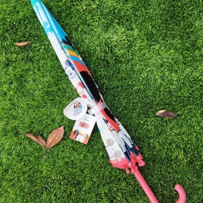 Guarda-chuva infantil com padrão da Disney e punho rosa sobre relva verde.