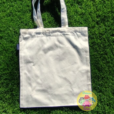 Saco de tecido branco com alças sobre relva artificial verde