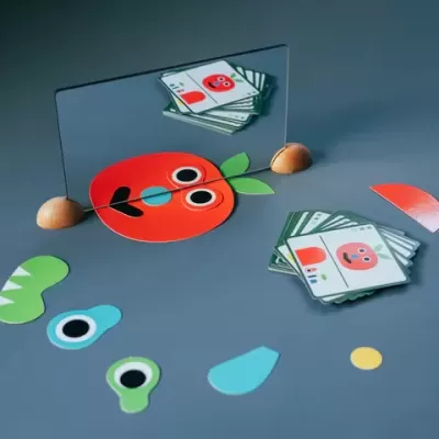 Espelho com cartas e peças coloridas formando uma cara de maçã