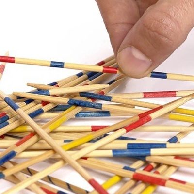 Mão a segurar pauzinho do jogo Mikado de madeira com riscas coloridas