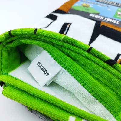 Toalha de praia Minecraft verde, branca e preta com embalagem azul e etiqueta visível
