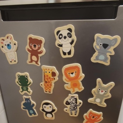 Imãs de frigorífico com desenhos de animais caricaturais coloridos num frigorífico cinzento.