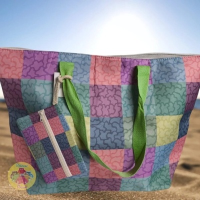 Mala de praia quadriculada colorida com estojo pequeno pendurado na areia junto ao mar