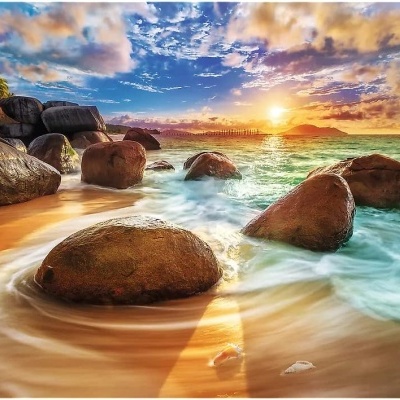 Praia com pedras grandes, mar azul e pôr do sol colorido