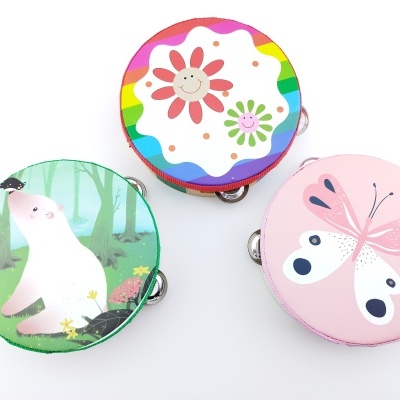 Três pandeiros infantis coloridos com desenhos de flor, borboleta e urso em fundo verde.