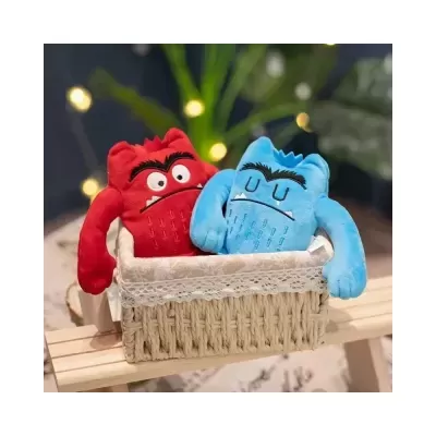 Bonecos de peluche vermelho e azul numa cesta de vime sobre madeira