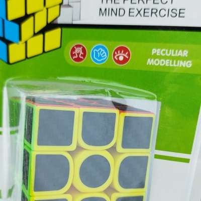Cubo mágico amarelo com adesivos pretos em embalagem verde