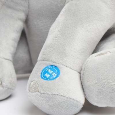 Pelúcia cinzenta com etiqueta azul PRESS ME na pata