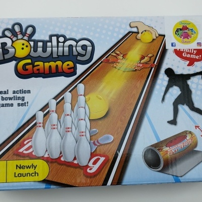 Caixa do jogo de bowling com pinos, bola amarela e pista impressa