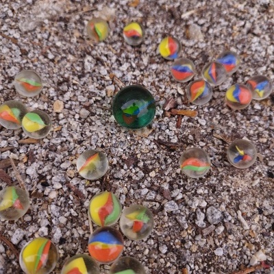 Bolas de gude coloridas sobre terra e cascalho