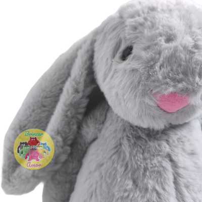 Pelúcia coelho cinza com nariz rosa e etiqueta Brincar com Amor