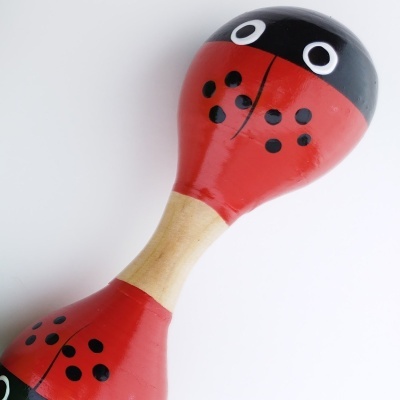 Maraca vermelha e preta em forma de joaninha com cabo em madeira