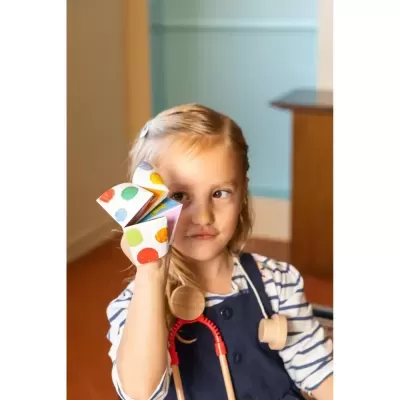 Criança segura brinquedo de papel com pontos coloridos e usa estetoscópio de brinquedo