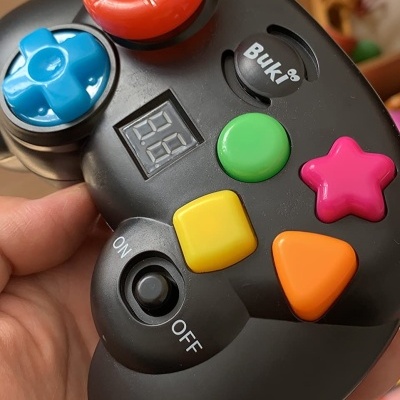 Comando de videojogo preto com botões coloridos e visor digital