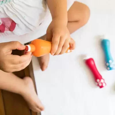 Frasco laranja em mãos de criança com pesos coloridos ao lado