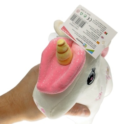 Pelúcia de unicórnio branca com chifre amarelo e orelhas rosa numa mão