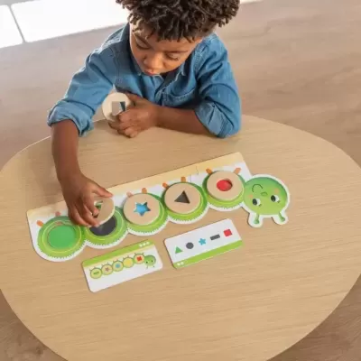 Jogo educativo de madeira com tabuleiro e peças em forma de lagarta e formas geométricas coloridas.