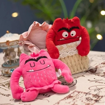 Dois brinquedos de peluche coloridos sobre toalha com carrossel ao fundo