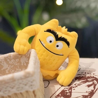 Pelúcia amarela de personagem com expressão sorridente junto a cesta de tecido com padrão floral