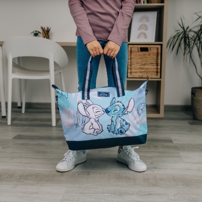 Mala azul claro com personagens Stitch e Angel da Disney, segurada por pessoa dentro de casa