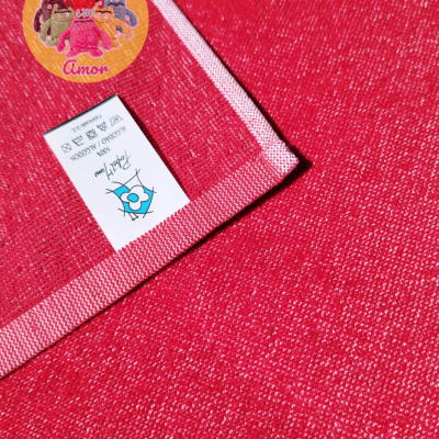 Toalha vermelha com etiqueta de instruções de lavagem e autocolante amarelo com bonecos