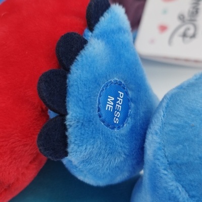 Brinquedo de peluche azul com botão 'PRESS ME' e etiqueta Disney
