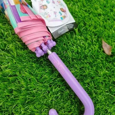 Guarda-chuva fechado com pega lilás e desenho colorido sobre relva verde