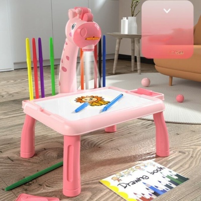 Mesa de desenho rosa com suporte de canetas girafa e livro de desenho ao lado em sala