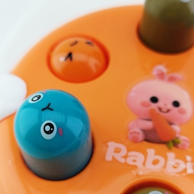 Brinquedo infantil de plástico laranja com peças coloridas e ilustração de coelho