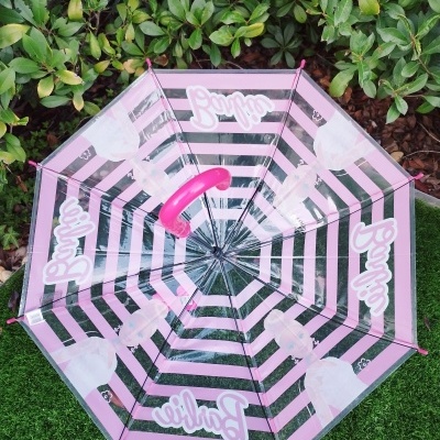 Guarda-chuva transparente com padrão riscas rosa e preto e imagens da Barbie