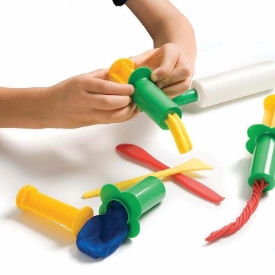 Conjunto de moldes de plástico coloridos para modelar massa com ferramentas sendo usadas por criança