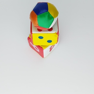 Brinquedos infantis em tecido colorido empilhados sobre fundo branco