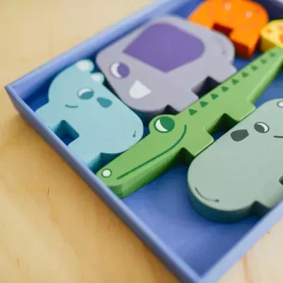 Peças de animais em madeira colorida numa caixa azul