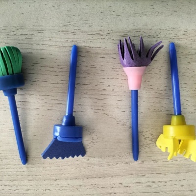 Ferramentas de plástico coloridas com pontas de esponja sobre madeira clara