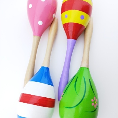 Quatro maracas de madeira coloridas com diferentes padrões, sobre fundo branco