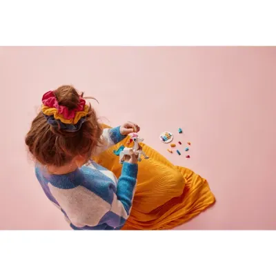 Criança com scrunchies coloridos brincando com blocos de montar